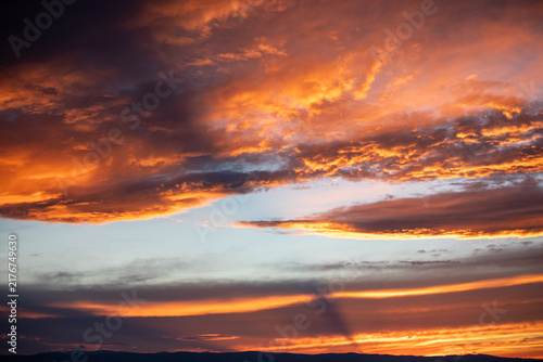 Fiery orange clouds over mountain silhouette at dawn