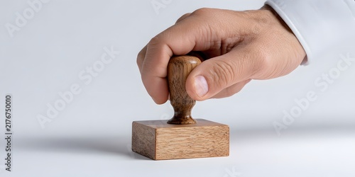 Hand pressing a wooden rubber stamp onto a clean white surface