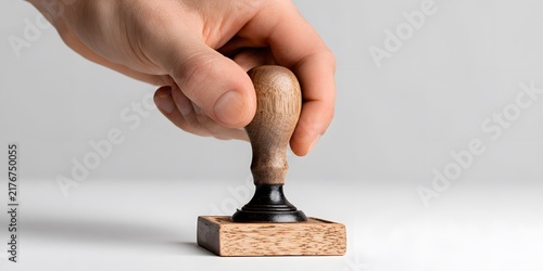 Hand holds wooden rubber stamp above blank white surface ready to make an imprint