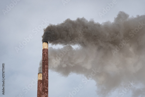 Canvas Print Chimneys of a heating plant releasing dark smoke into the atmosphere against the sky