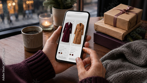 Person browsing clothing options on a smartphone near a window  