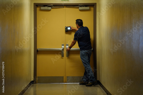 Obraz na płótnie Fire Door Inspector Testing Closing Cycle in Institutional Corridor