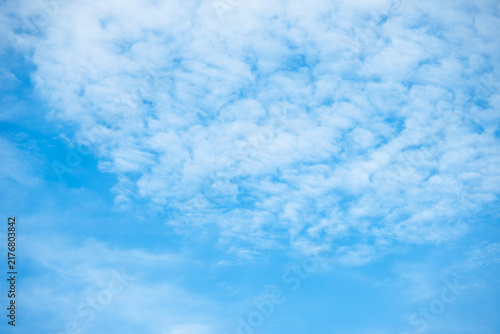 Scenic blue sky with scattered soft white altocumulus clouds on a bright sunny day. Natural cloudscape with clean copy space for digital and print graphic design.