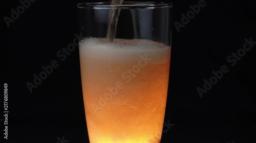 Closeup hoppy unfiltered beer foaming in glass. Foam alcohol beverage flowing clean goblet on black background. Fresh craft heady liquid bubbling in full transparent mug.