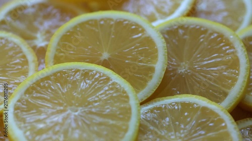 Yellow lemon slices piled togather, close shot. Rotative background. 