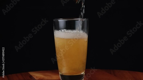 Closeup hoppy unfiltered beer foaming in glass. Foam alcohol beverage flowing clean goblet on black background. Fresh craft heady liquid bubbling in full transparent mug.