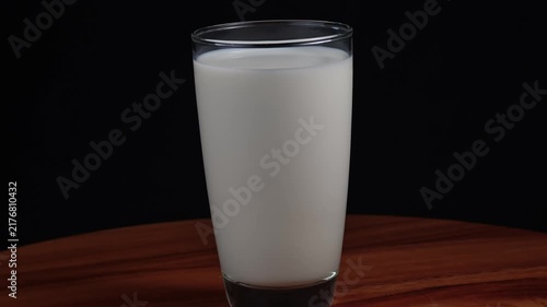 Milk in a tall glass on a black background.