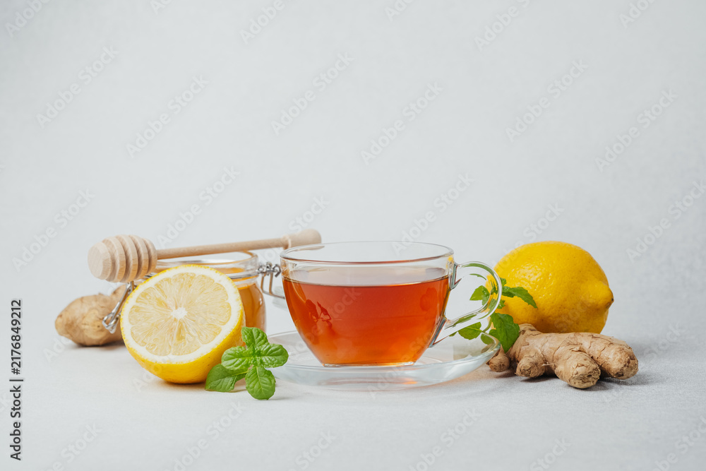 Naklejka premium Cup of tea with lemon, ginger and honey on a light background