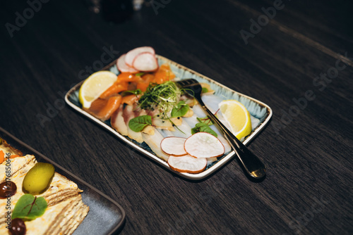 Fotografie Fish platter with lemon and radish on dark background