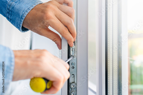 Cuadro en lienzo Professional technician tightens screw on open plastic window metal mechanism with screwdriver indoors