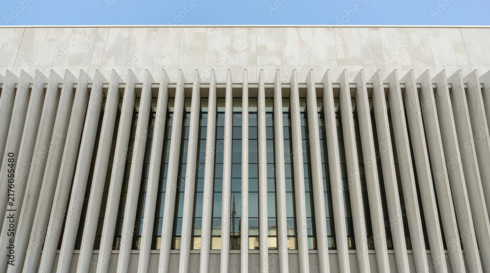 Naklejka premium Modern concrete facade with vertical sunshade fins framing reflective windows
