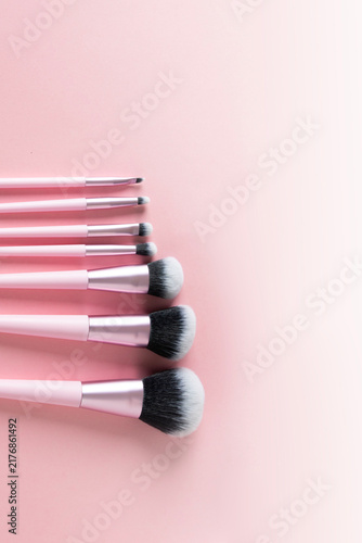 Bild auf Leinwand Set of pink-handled makeup brushes, featuring different sizes and brush heads, are artfully laid out in a straight line on a pale pink surface