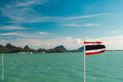 Foto Thai Flag Over Turquoise Sea and Mountainous Coastline