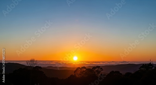 Sunset over a landscape with trees and hills illustration