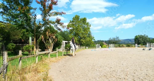 Beautiful young female rider trotting on her horse 