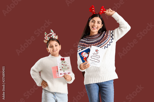 Happy mother and her daughter with Christmas greeting cards on brown background