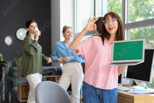 Female Asian programmer with laptop showing OK in office