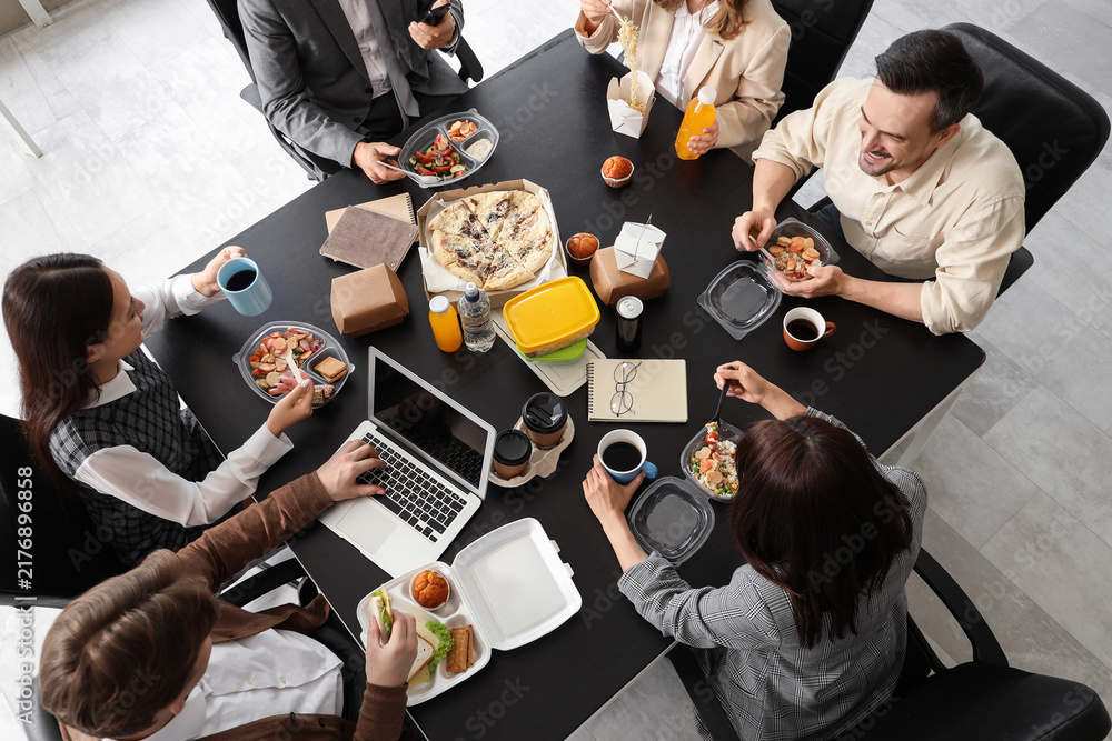 Obraz premium Group of business people having lunch at table in office, top view