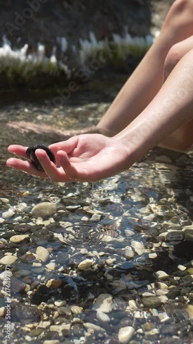 Hand rock water, close up of a woman holding a stone over a clear ocean shoreline for summer travel and vacation concept