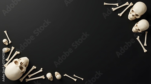 Human skulls and scattered bones forming a frame on a dark black background for halloween design