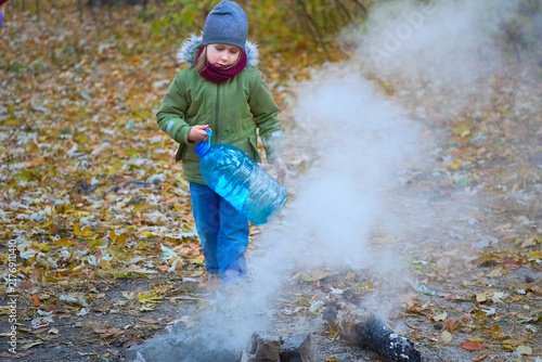 Camp.Child puts out a fire after picnic in autumn forest