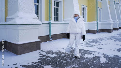 Fotografía Woman walks in winter clothing near a building covered in snow in a cold environ