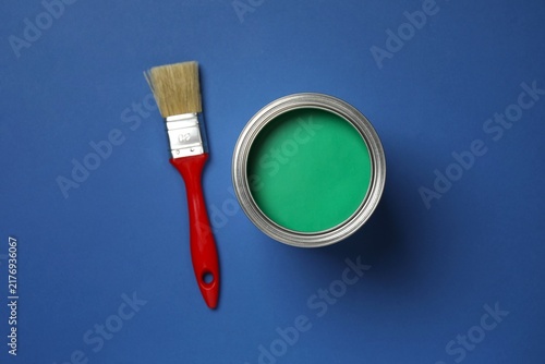 Obraz na płótnie Can of green paint and brush on blue background, top view