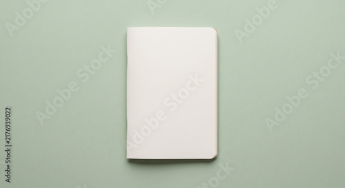 Blank white paper notebook with hardcover mock up top view on solid pastel green background with copy space for design layout