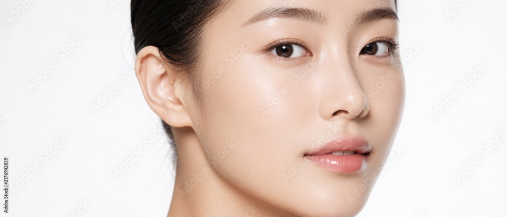 Fototapeta premium close up beauty portrait of a young asian woman with smooth glowing skin, natural makeup and glossy lips against a clean white studio background