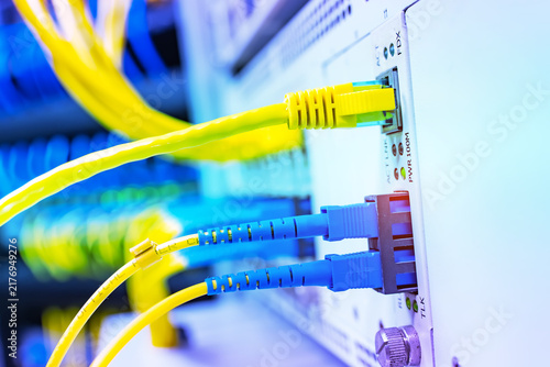 Fotografie Fiber Optic cables connected to an optic ports and Network cables connected to e