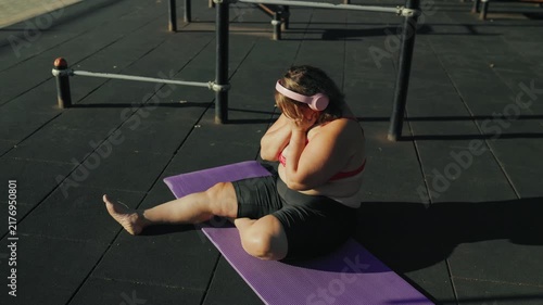 High angle view of an exhausted obese woman resting on a fitness mat.