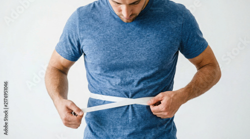 Man in a blue t-shirt measuring his waist with a tape measure against a generated using ai