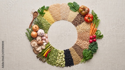 Assorted grains and fresh vegetables arranged in a circle on linen
