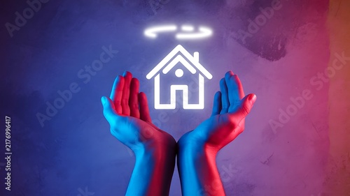 Hands protecting a glowing house symbol representing home security, safety and family protection