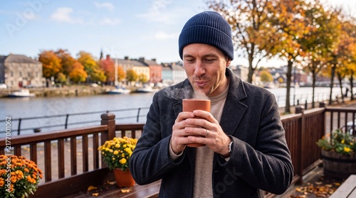 Man Enjoying Hot Steaming Coffee on Autumn Waterfront Promenade