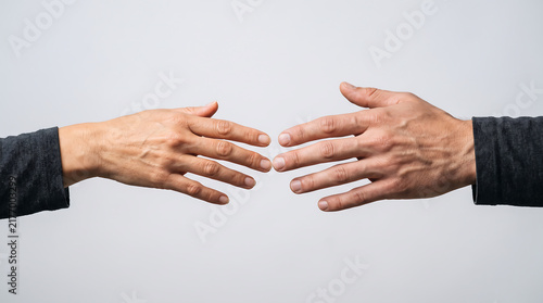 Close up of two human hands reaching toward each other on a neutral background, symbolizing connection, relationship, support, love, and human interaction.