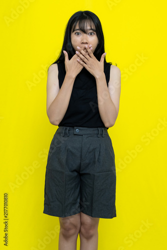 Quadro su tela Shocked Young Asian Woman Wearing Black Sleeveless Top Covering Mouth Against Br