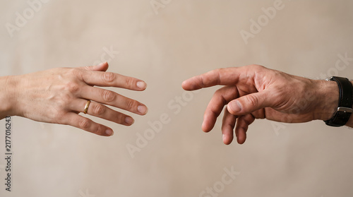 Two human hands reaching toward each other without touching, symbolizing connection, support, trust, hope, emotional distance and human relationships.