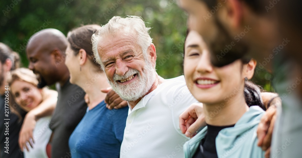 Fototapeta premium Diverse group of people smiling and standing arm in arm outdoors.