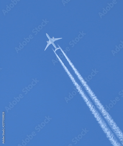 Fotografie High in the blue sky, a white twin‑turbine aircraft is flying