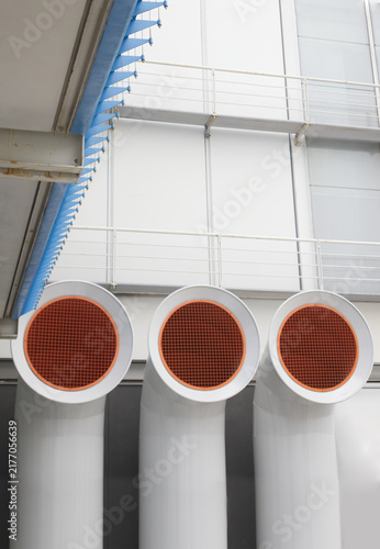 Modern Industrial Ventilation Pipes with Orange Grids on White Building Exterior