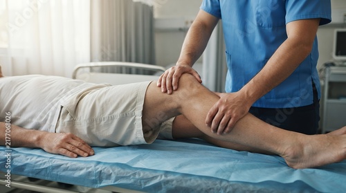 Professional physiotherapy session for knee injury recovery, male physical therapist treating patient leg in clinic, orthopedic rehabilitation
