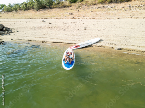 Woman relaxing on paddleboard near sandy shore