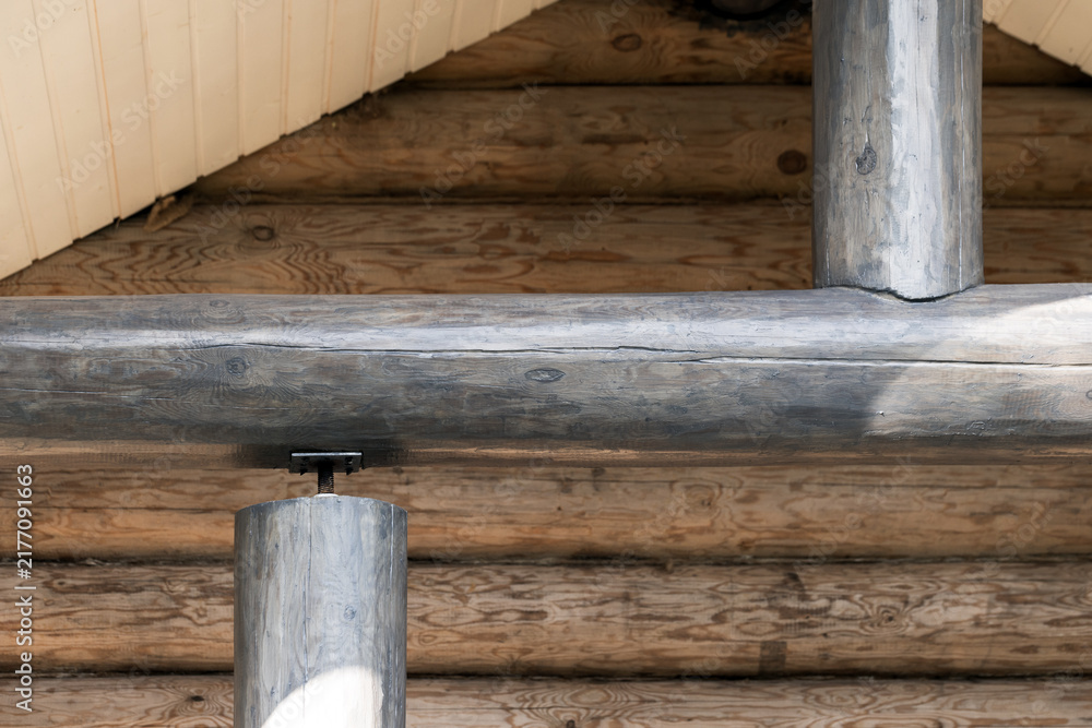Obraz premium Rustic log cabin interior featuring exposed wooden beams and round timber support columns, emphasizing natural wood grain, weathered texture and traditional joinery for a cozy handcrafted architecture