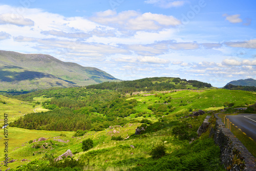 A green hill and mountain landscape with a winding road on Moll's Gap in County Kerry, Ireland.