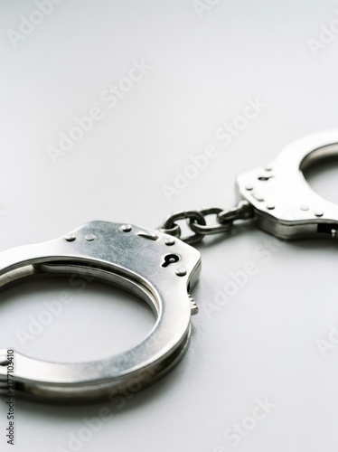 Steel handcuffs lying on white table in police station. Law enforcement and justice concept. Crime investigation, arrest and detention symbol for legal or security background.