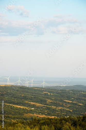 Photography Wind turbines on green hills generating clean renewable energy under blue sky