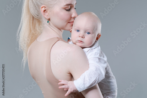Canvastavla Young caucasian mother tenderly kissing her baby boy on the head in a studio, id