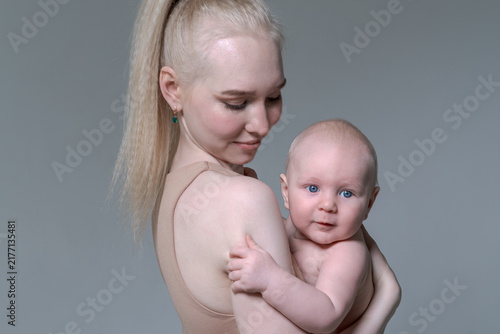 Bild auf Leinwand Young caucasian mother tenderly holding her bare baby boy over her shoulder in a
