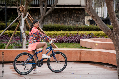 Teen Girl Sitting on Her Bicycle Looking Back in a City Park